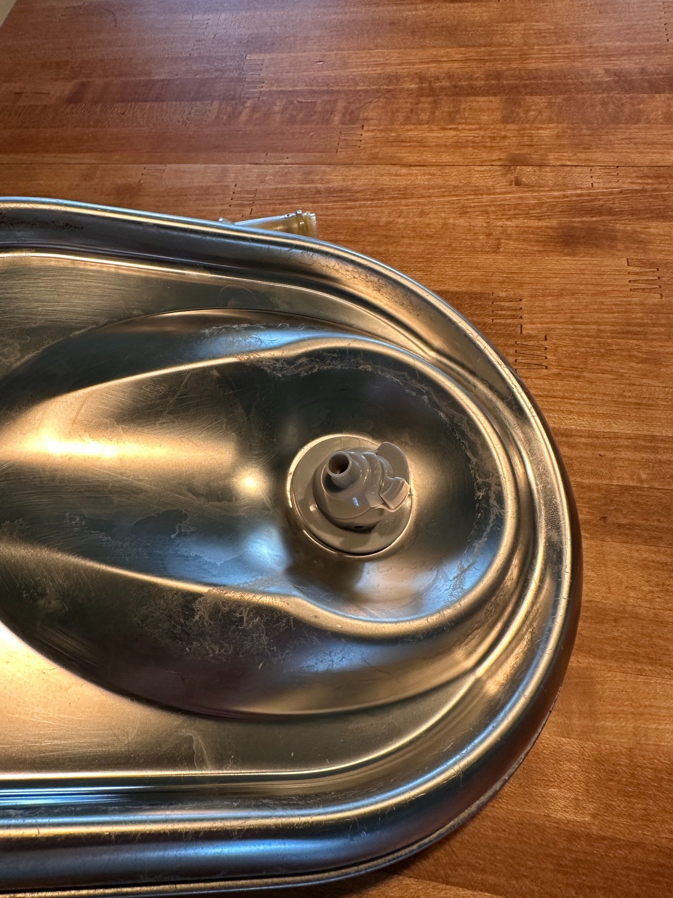 Gray dispenser correctly installed above the stainless-steel drinking tray