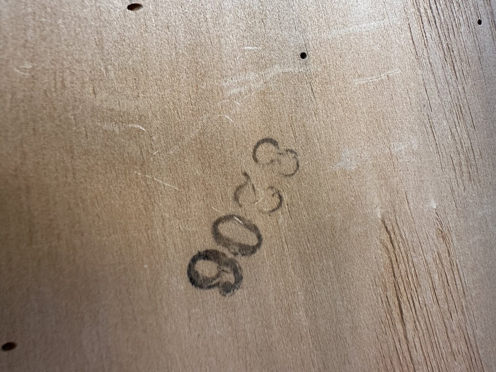 Faint black factory numbers stamped on the underside of a chair seat