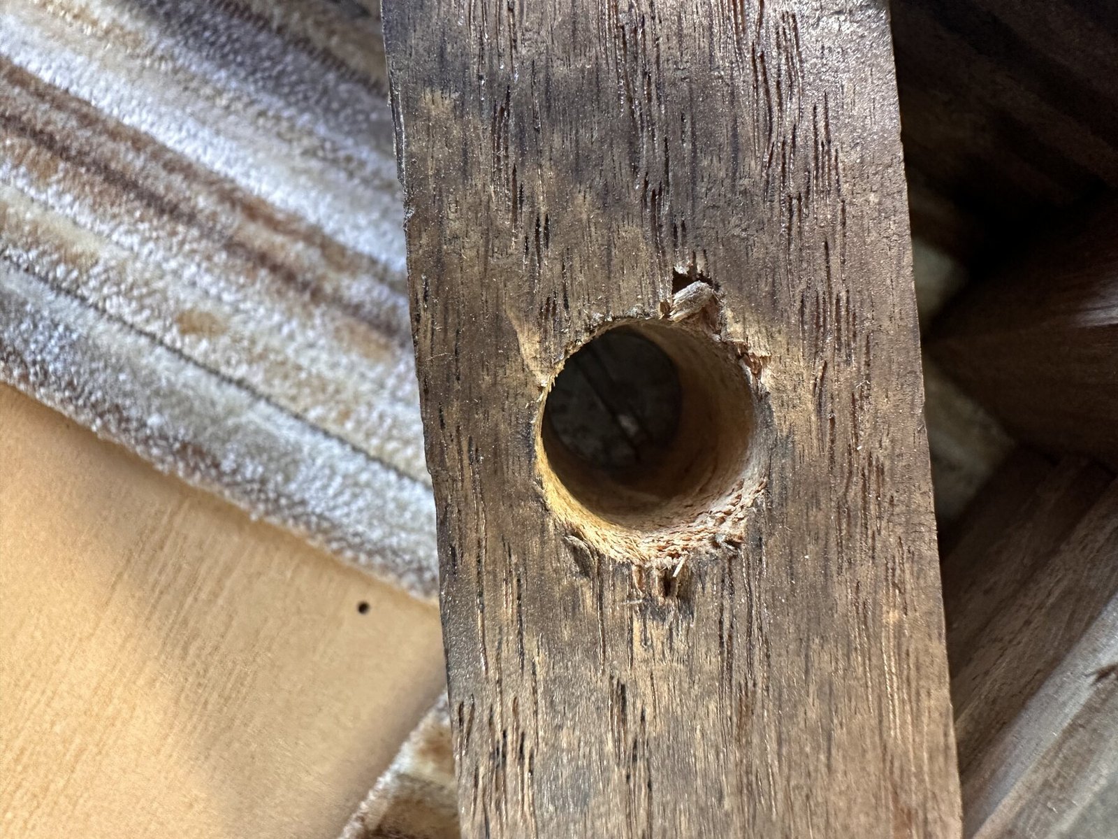 Close-up through an enlarged drilled hole in a chair brace