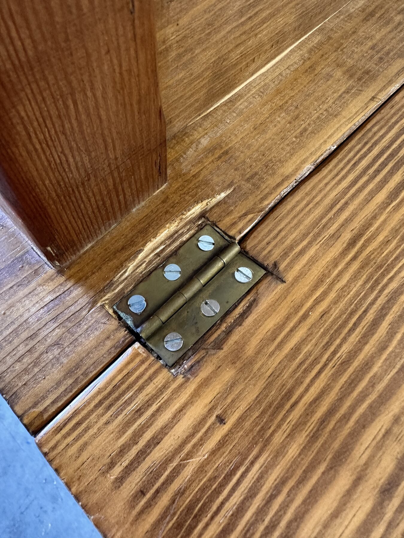 Straight-on close-up of another drop-leaf hinge and its six slotted screws