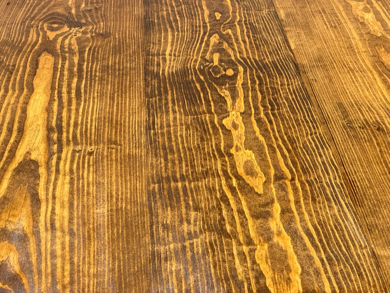 Close-up of dark and golden grain with knots and small marks under clear finish