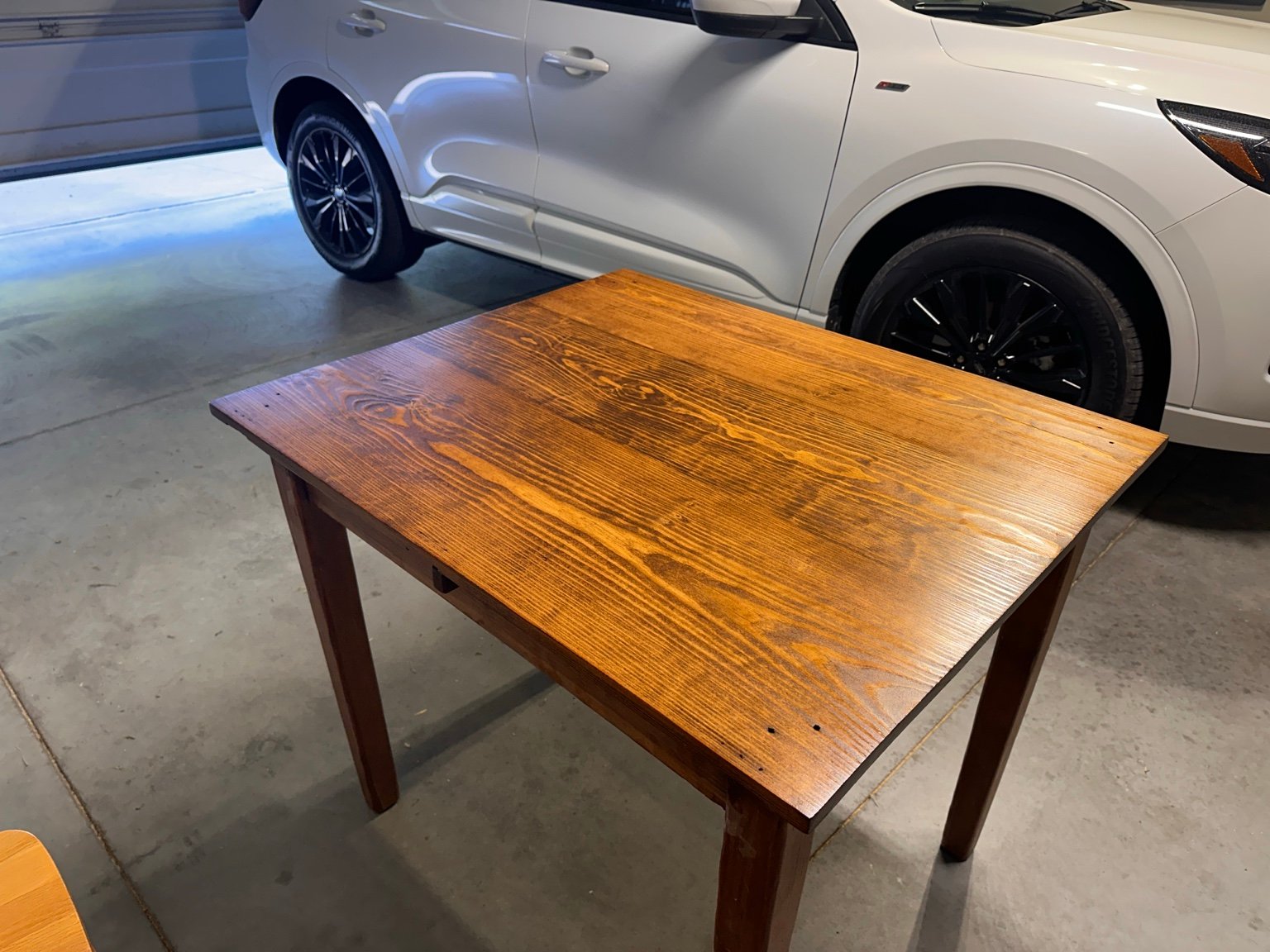 Right-front diagonal view of the table beside a white vehicle after coat four