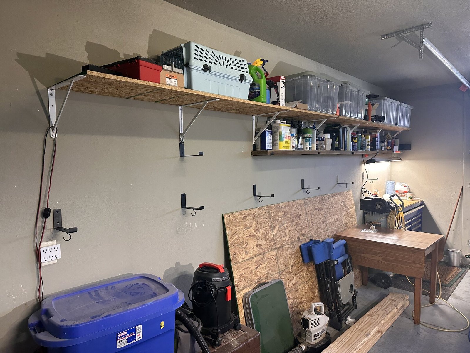 Wide garage wall view showing shelves, brackets, and workspace