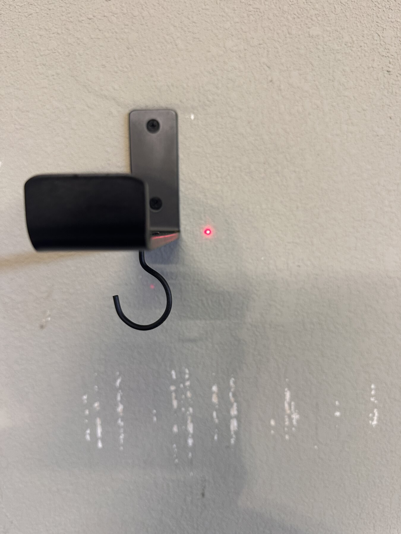 Close-up of hook shelf bracket with red laser level dot