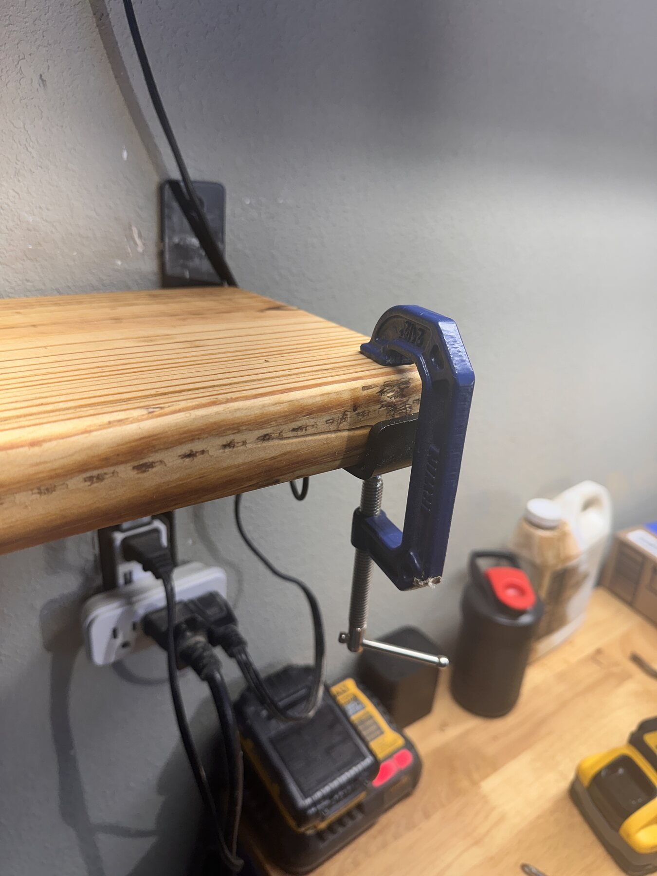 Close-up of clamp holding pine shelf end on bracket