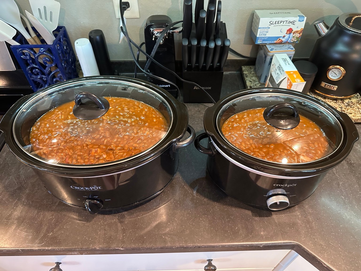 Two full Crock-Pots of baked beans sitting side by side on the kitchen counter