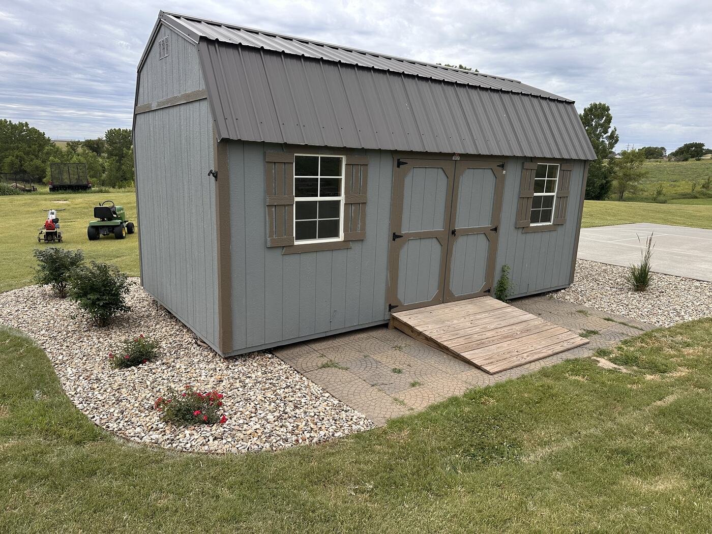 Front of the shed surrounded by newly installed rock beds and plants